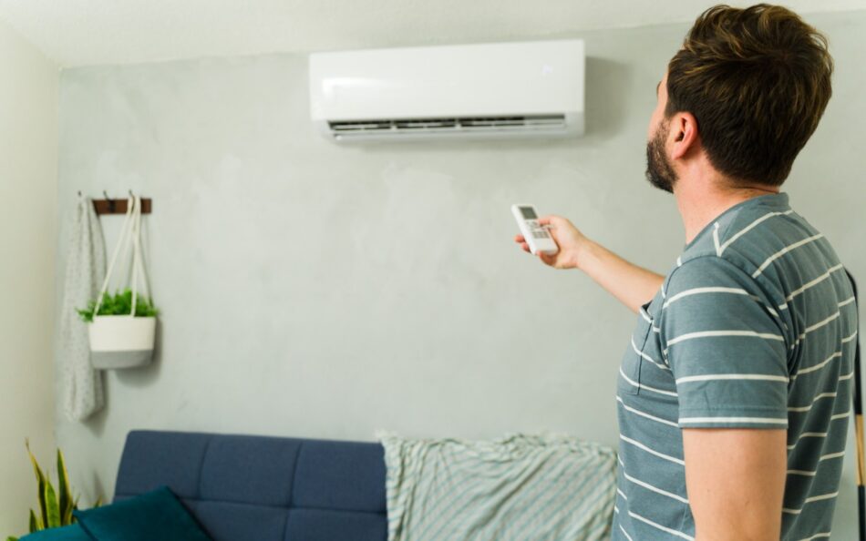 Man using remote to turn on ductless air conditioner at home