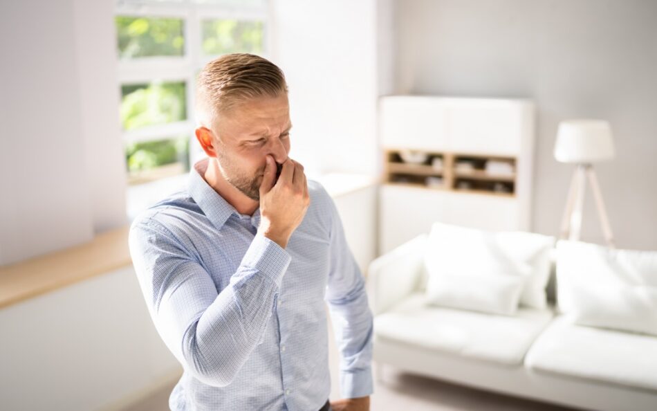 Man smelling unpleasant odor in living room.